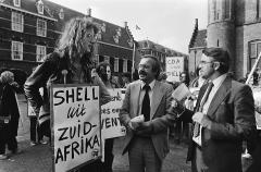 Kamerleden Ter Beek en Jan Nico Scholten bij een demonstratie op het Binnenhof, waar iemand een bord met "Shell uit Zuid-Afrika" omhoog houdt.